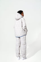 A model shown from the back wearing a light gray quilted puffer jacket and matching pants with a thin blue piping accent, set against a plain white studio background.