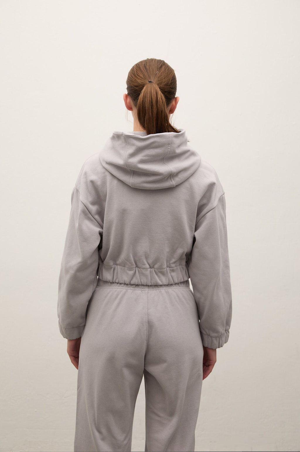 Person wearing a gray tracksuit from behind on a white background