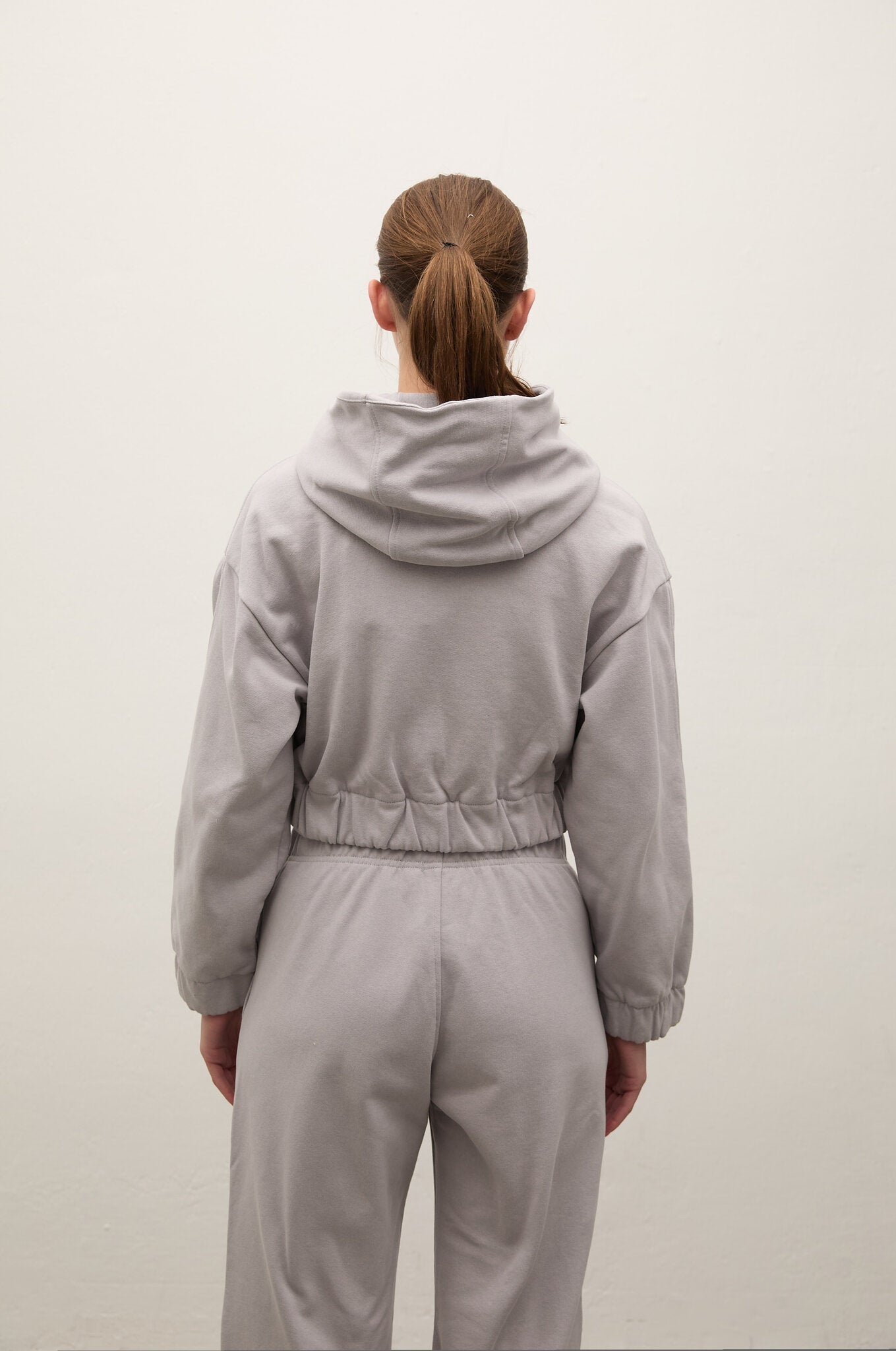 Person wearing a gray tracksuit from behind on a white background