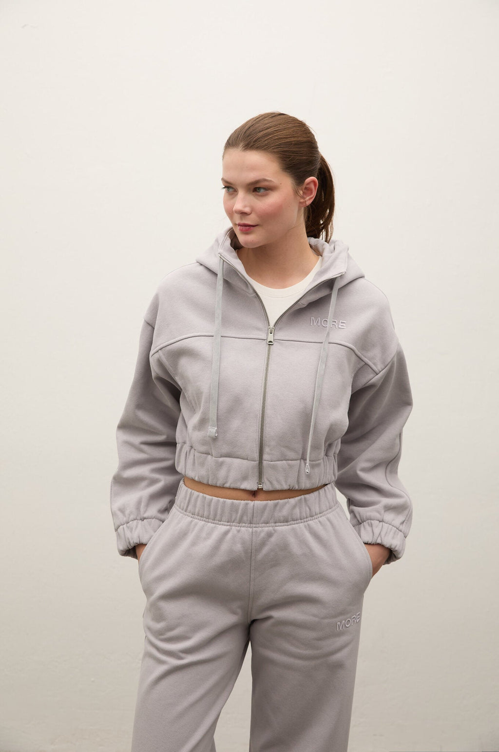 Woman wearing a light gray tracksuit against a plain background