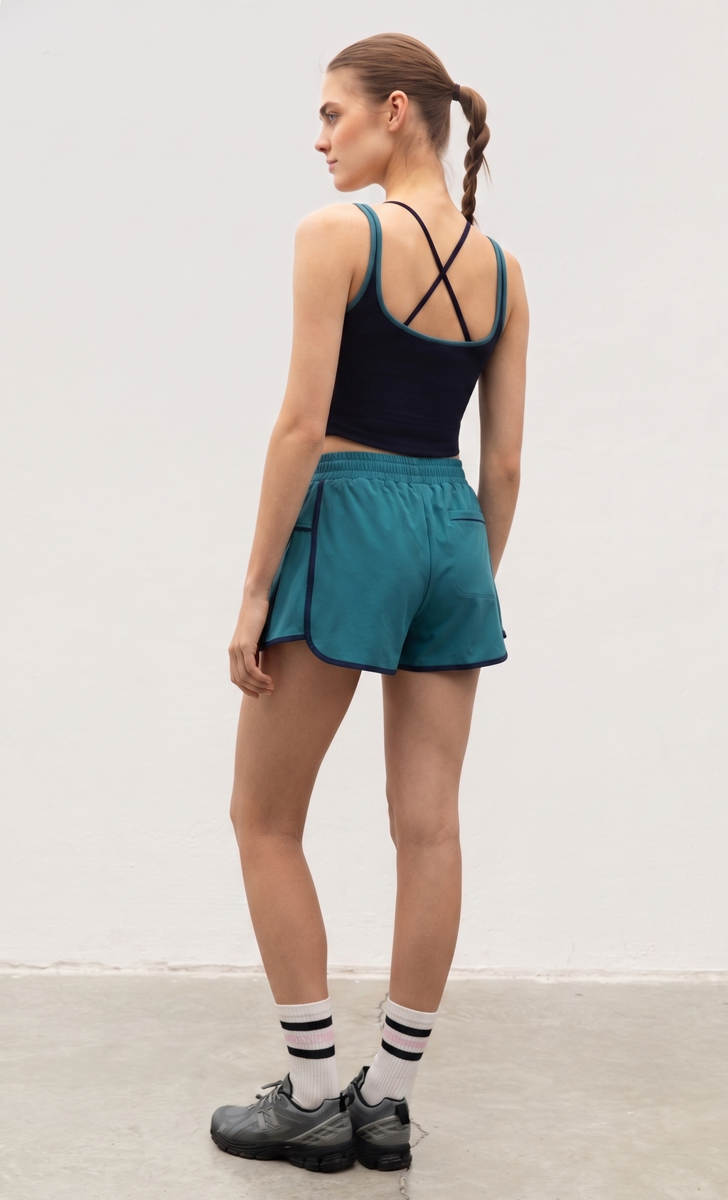 Woman wearing a black tank top and teal shorts on a white background