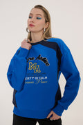 Woman wearing a blue and black sweatshirt with text and graphics on a white background