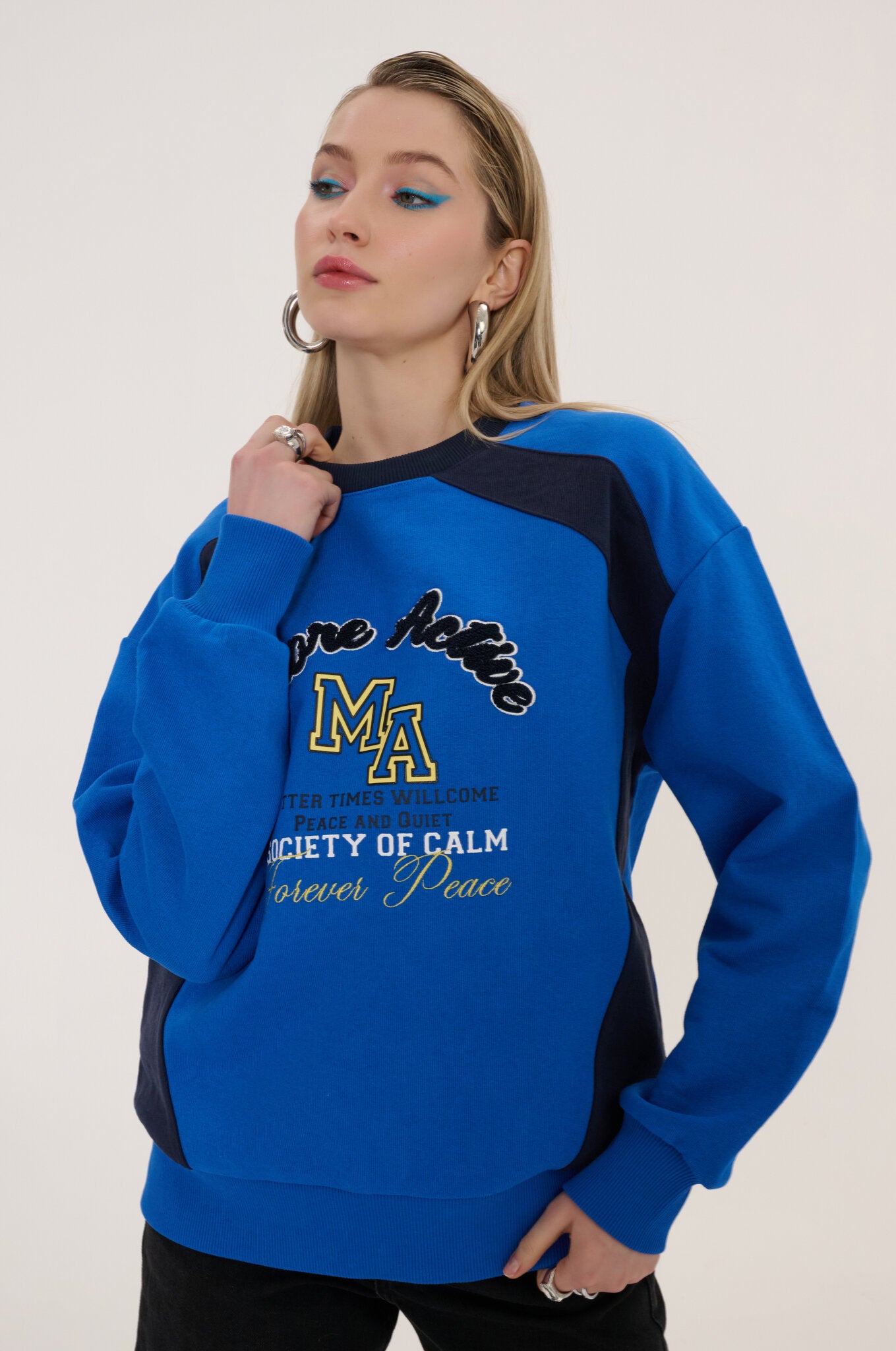 Woman wearing a blue and black sweatshirt with text and graphics on a white background