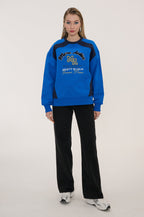 Person wearing a blue and black tracksuit with visible branding on a white background