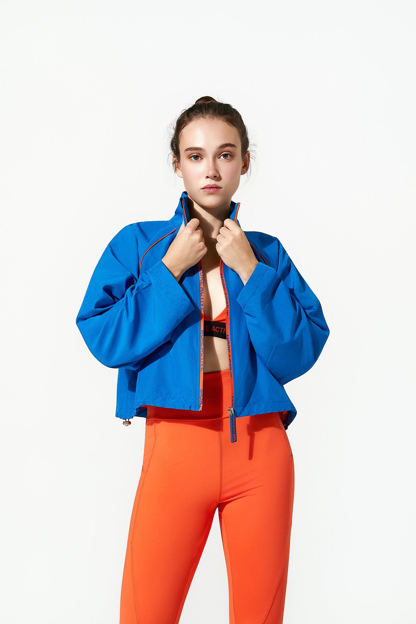 Person wearing a blue jacket and orange pants on a white background