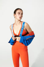 Woman wearing a colorful outfit with a blue strap over her shoulder on a white background