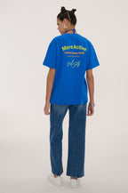 Person wearing a blue t-shirt with text and graphics on the back, standing against a plain background.