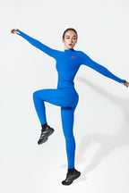 A woman modeling a bright blue Gym Leggings with black sneakers, posed dynamically against a clean white studio background.