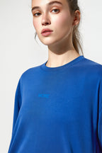 Person wearing a blue sweatshirt with 'MORE' text on a plain background