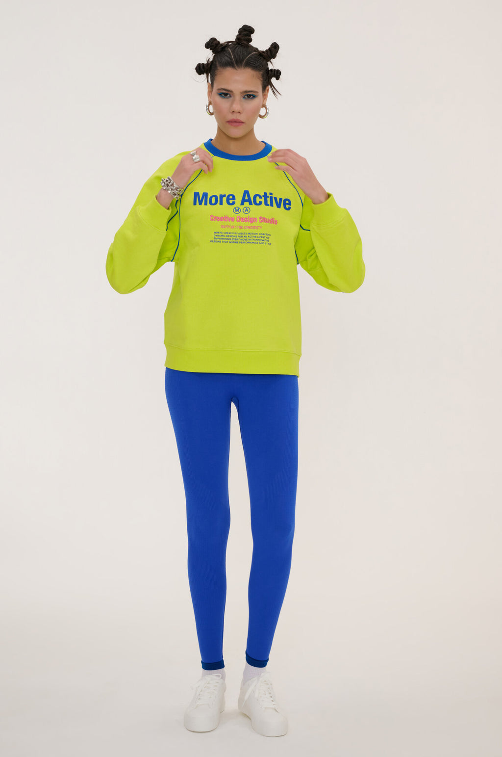 Person wearing a bright green sweatshirt with text and blue leggings on a white background