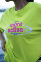 A close-up of a person wearing a bright neon yellow-green t-shirt with a pink and white graphic that reads 'more active' and 'Designed & Produced by More Active'.