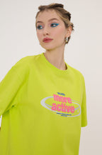 Person wearing a bright green t-shirt with a logo and text on a plain background