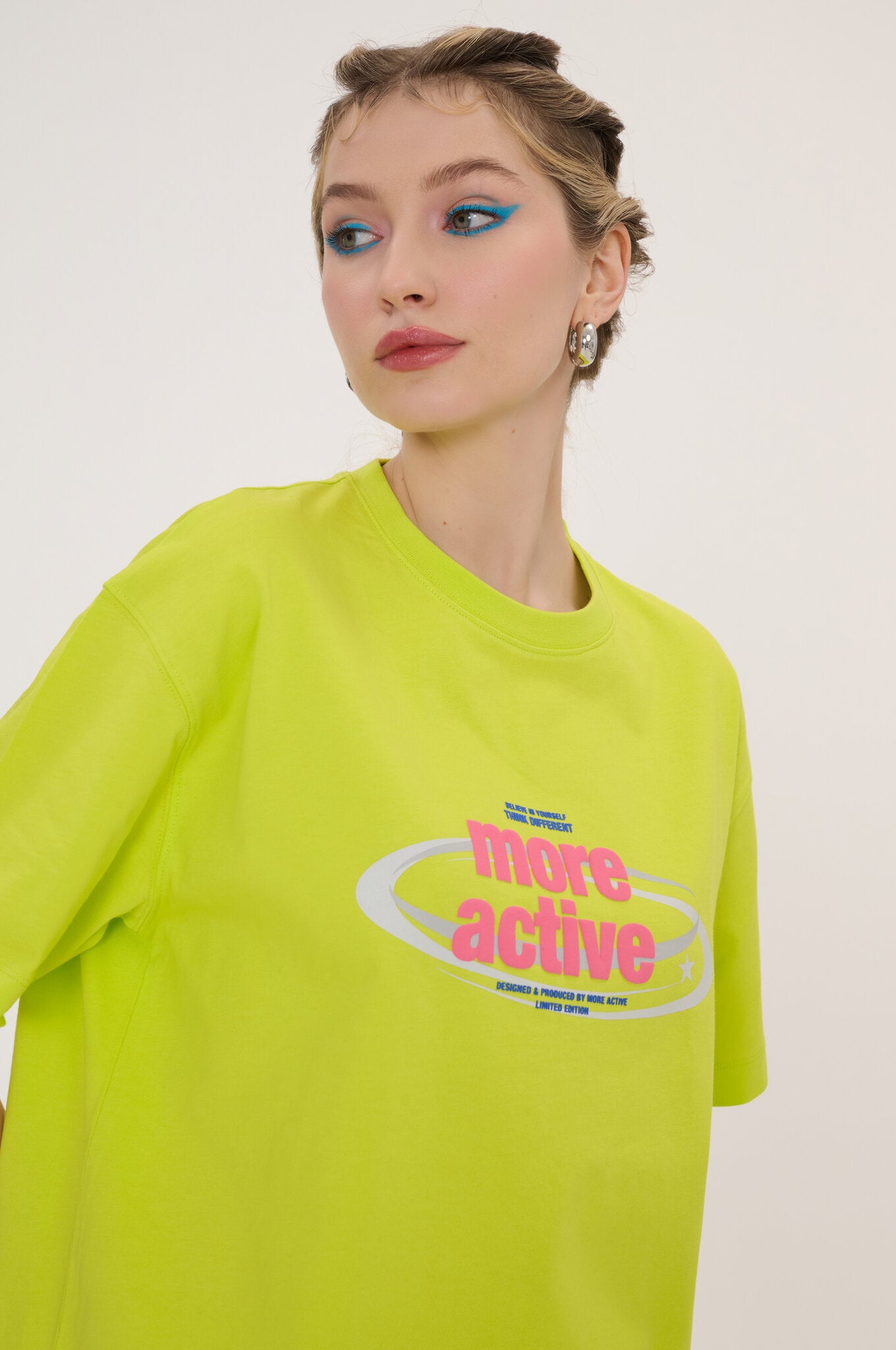 Person wearing a bright green t-shirt with a logo and text on a plain background