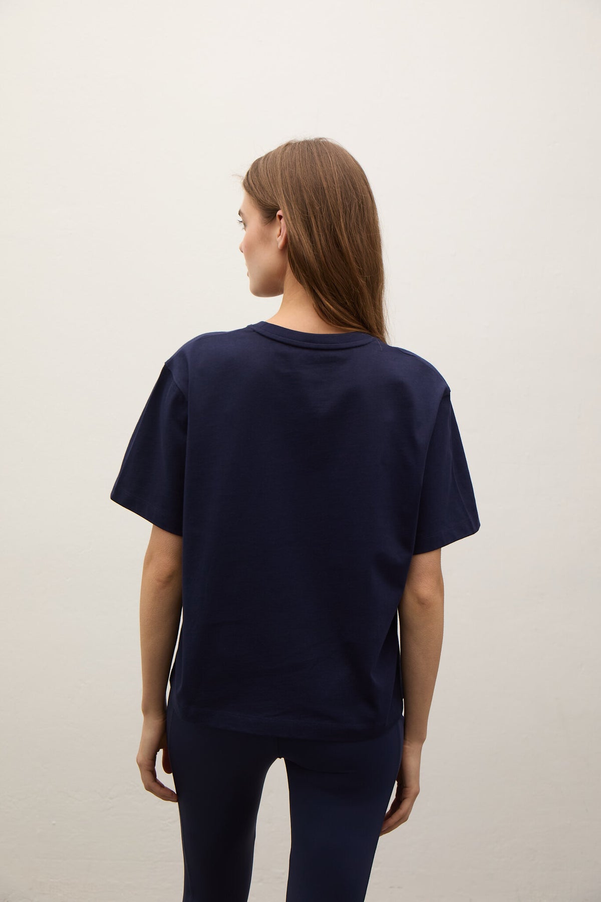 Person wearing a navy blue t-shirt and pants on a plain background