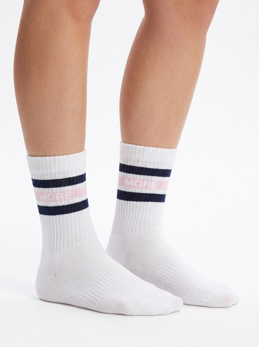Model wearing white half-crew throwback socks with a maritime blue and ballerina pink double stripe