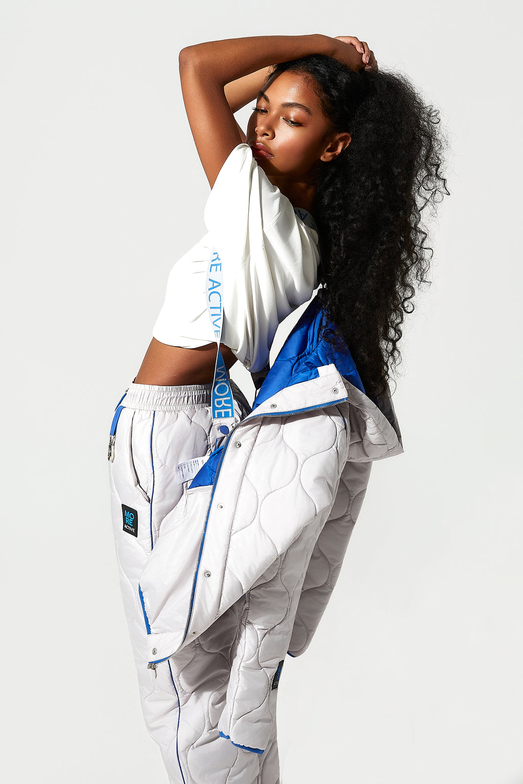 model wearing a white and blue womens puffer jacket with visible  More Active branding, side view