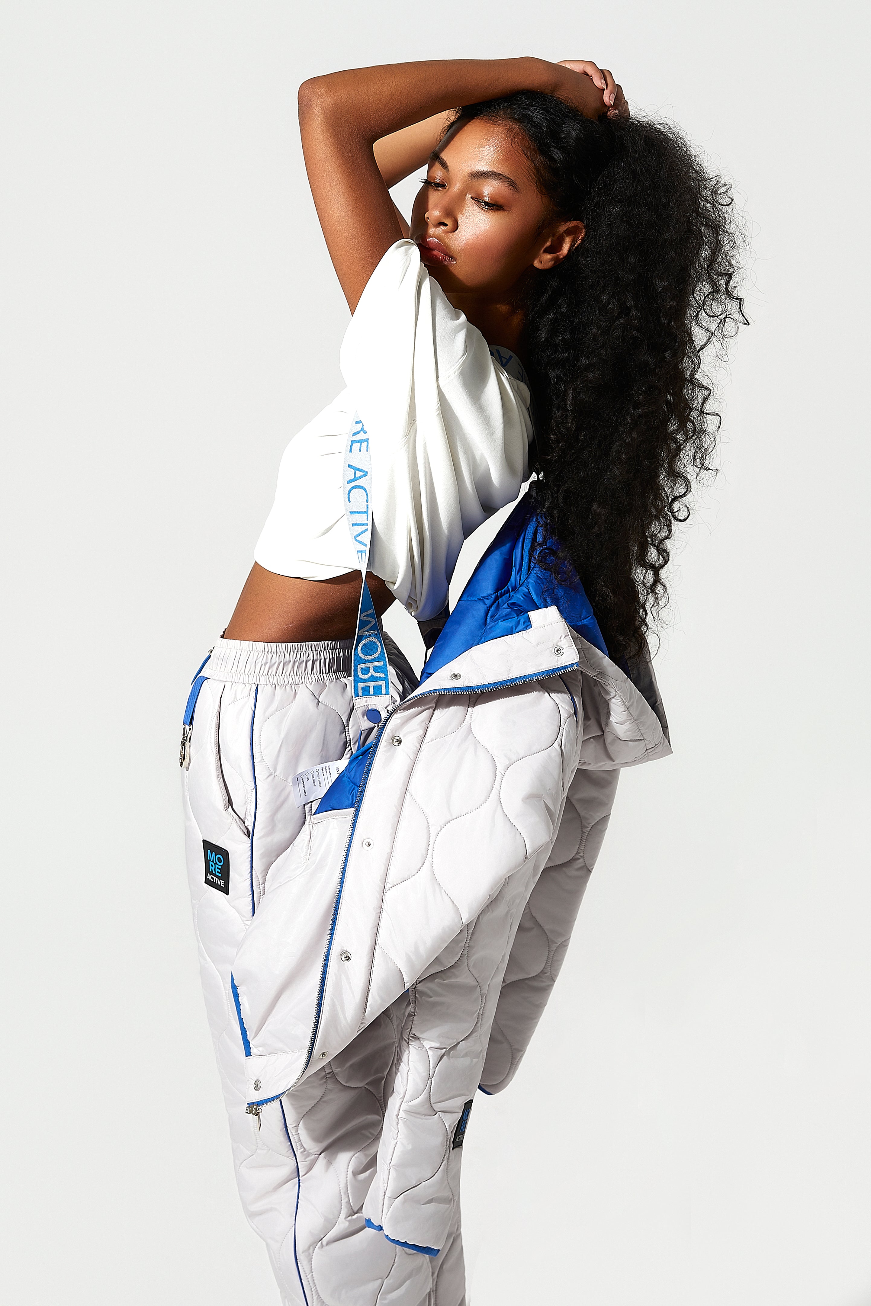 model wearing a white and blue womens puffer jacket with visible  More Active branding, side view