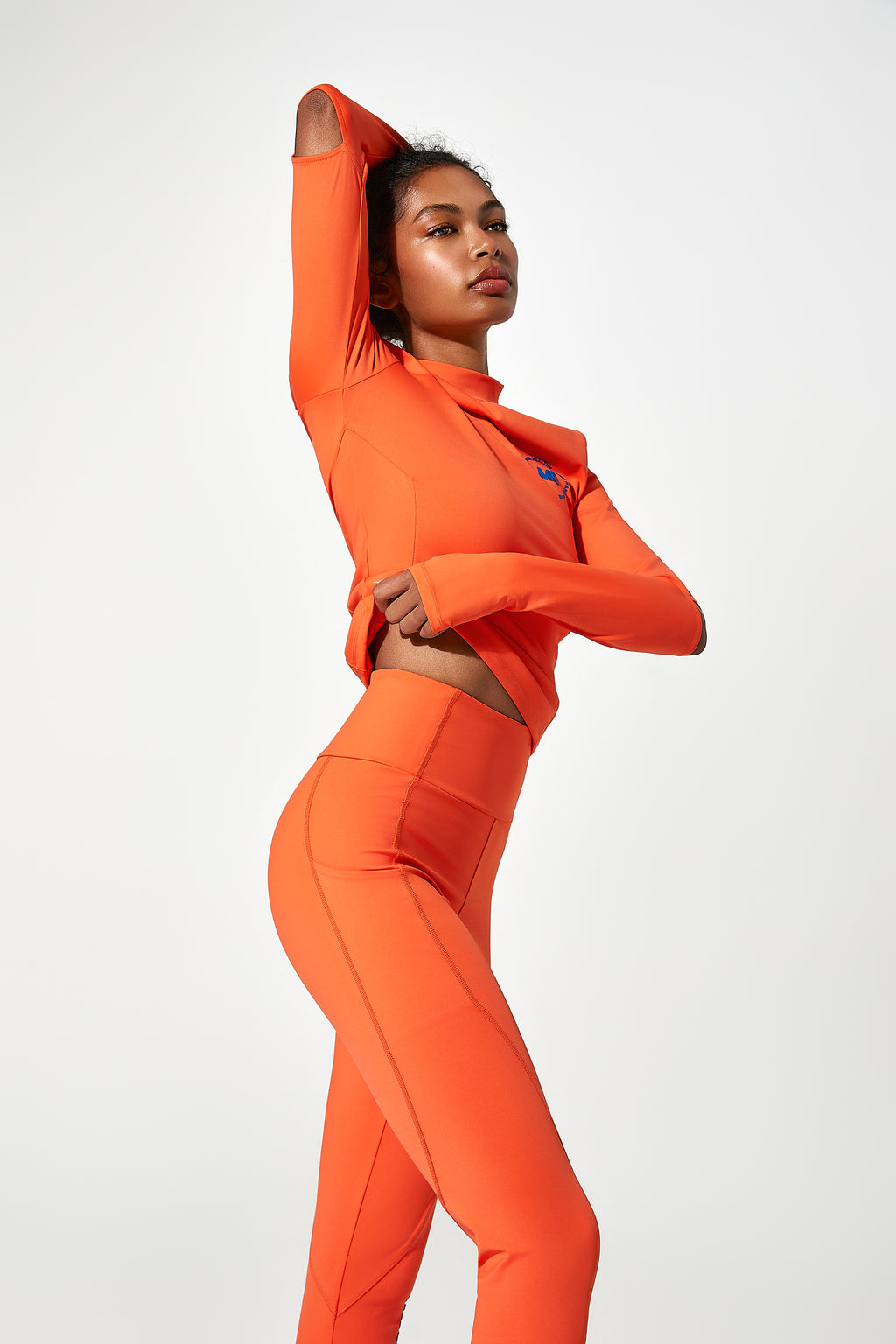 model wearing an orange womens running tops​ orange running leggings with phone pocket