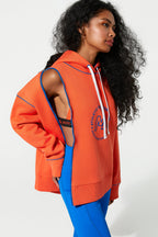 Woman wearing an orange hoodie with a cutout design on a white background