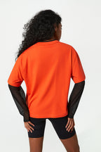 Person wearing an orange shirt with black sleeves on a white background