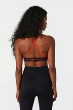 Person wearing a black sports bra with red straps and black leggings on a white background