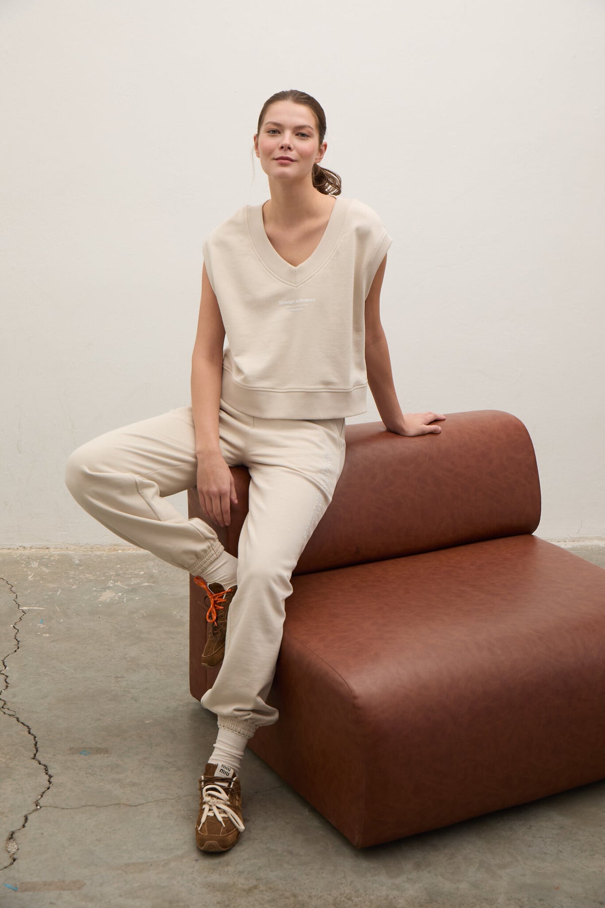 Person sitting on a modern brown chair against a plain wall