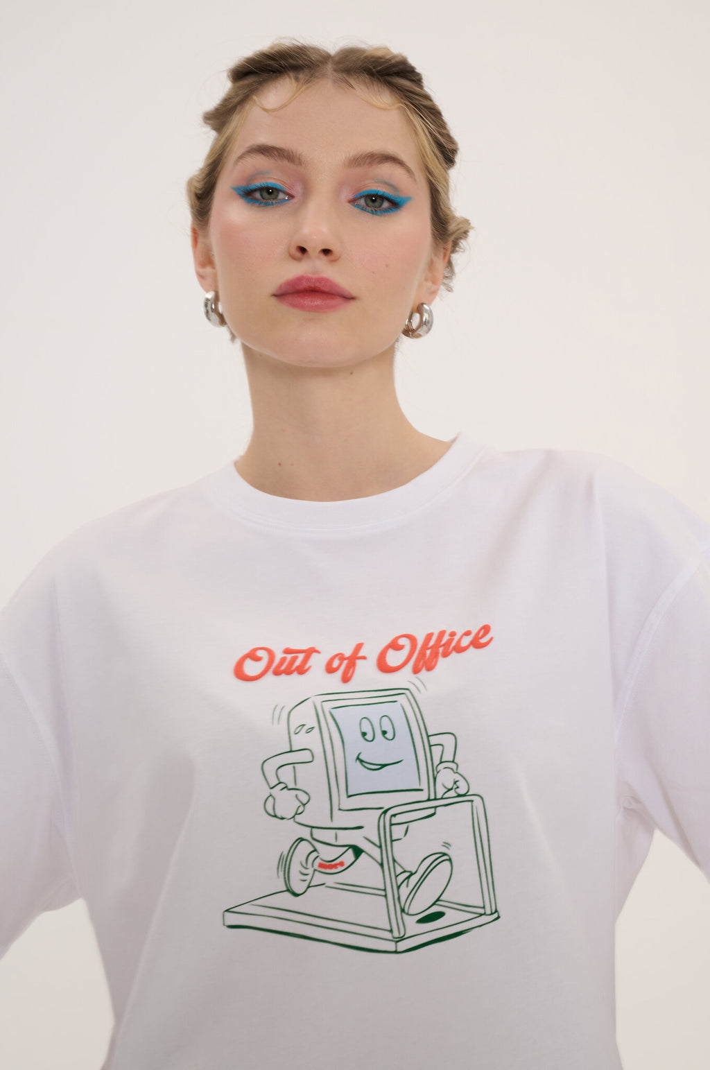 Person wearing a white sweatshirt with a graphic design and text 'Out of Office' on a plain background