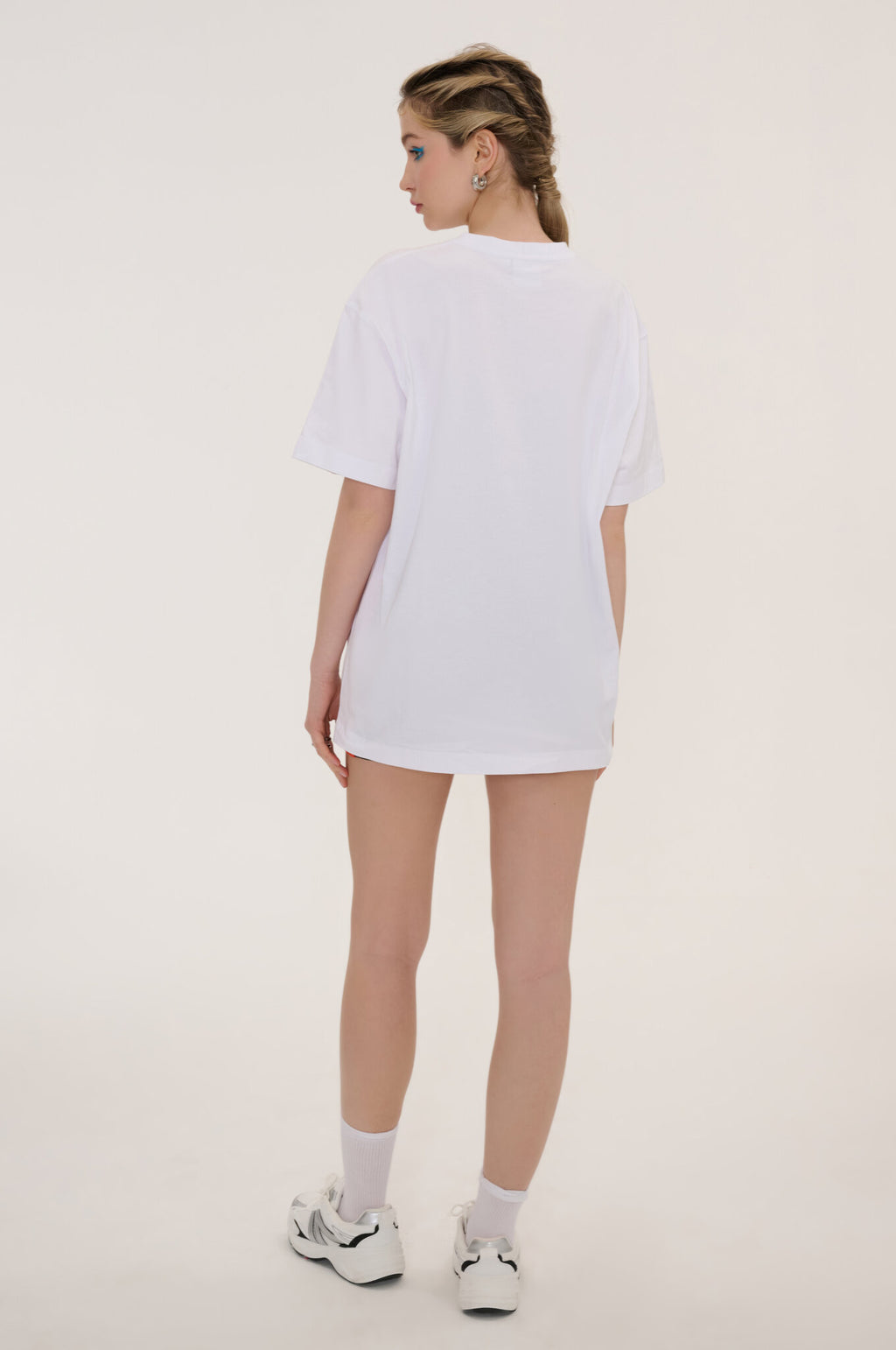 Person wearing a white t-shirt and shorts on a plain background