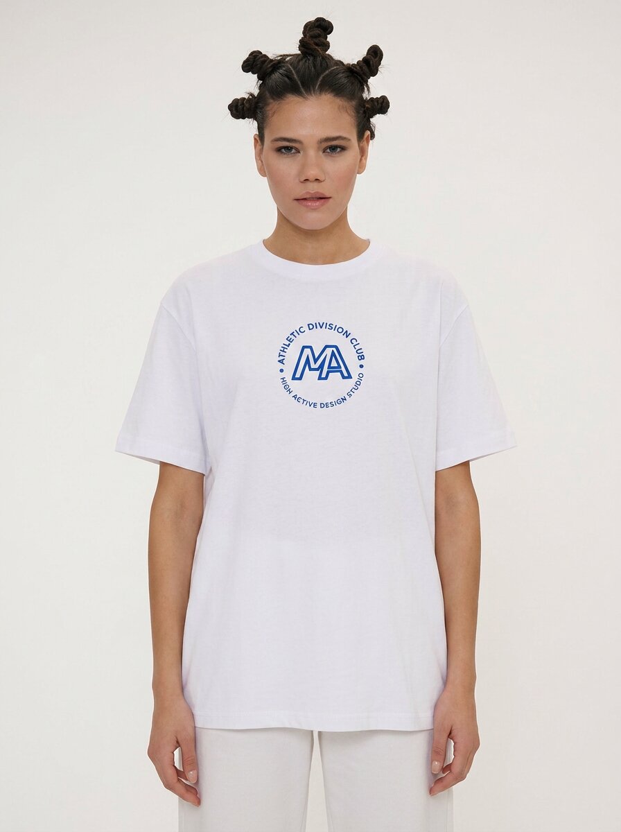 A model wearing a white short-sleeve t-shirt with a blue circular graphic on the chest that reads 'A LIFELONG DIVISION CLUB' around a large 'MA' monogram, paired with white pants against a plain light background.